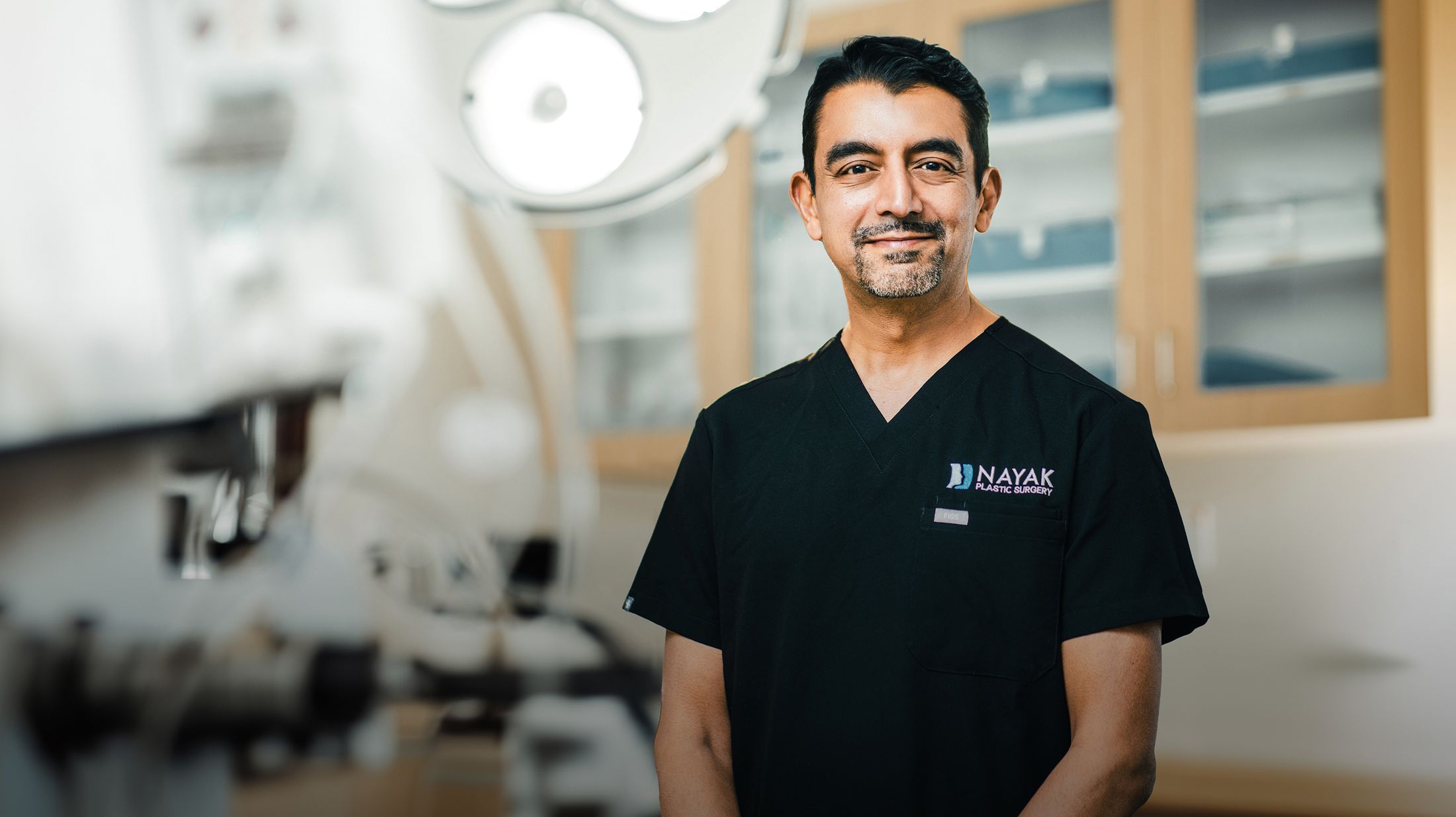 Doctor in surgical scrubs smiling in clinic.