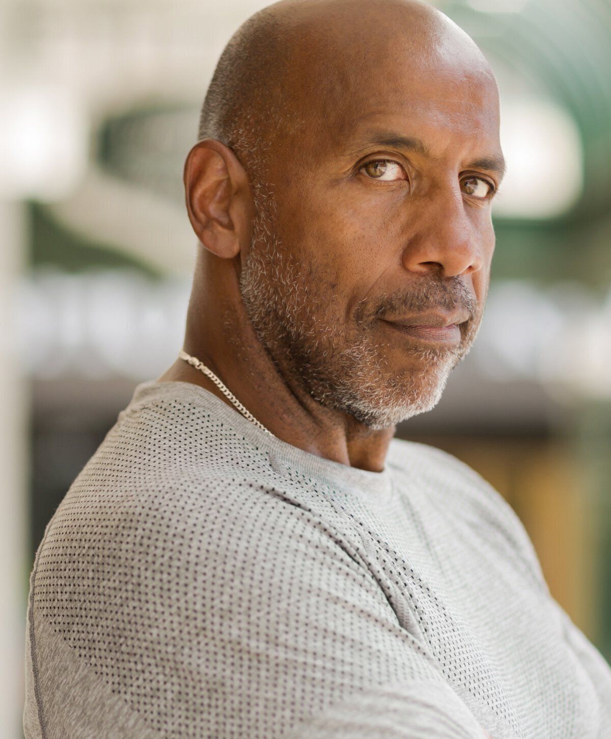 St. Louis Gynecomastia Surgery model with serious expression in gray shirt.
