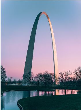 Gateway Arch at sunset by a tranquil pond.