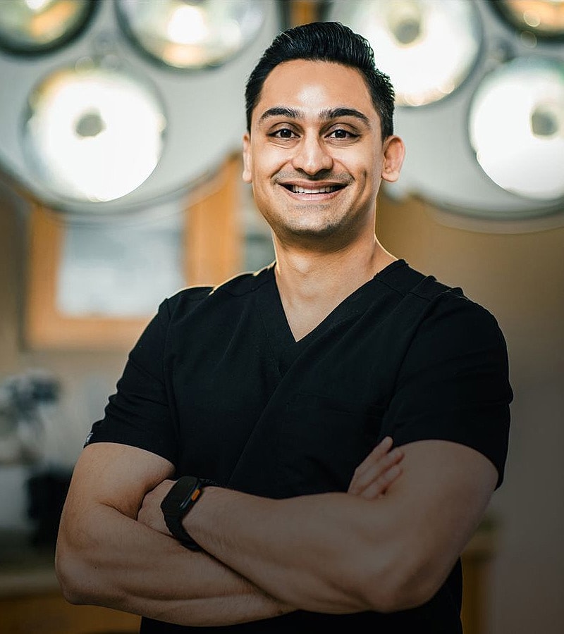 Smiling medical professional in scrubs, arms crossed.