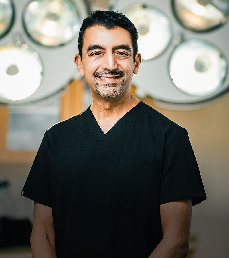 Smiling doctor in surgical scrubs with lights.