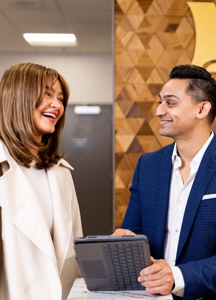 Two professionals smiling and discussing in office.