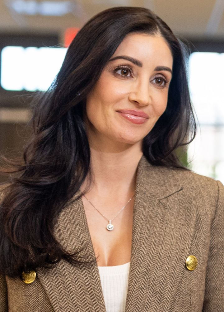Smiling woman in brown blazer and necklace.