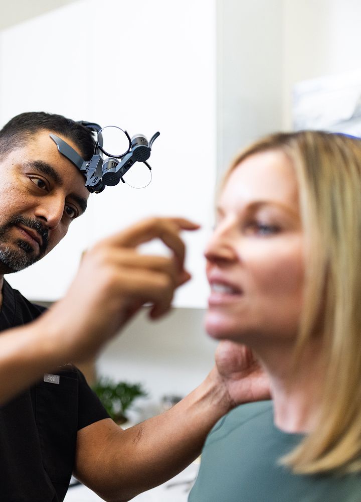 Medical professional examining a patient's face closely.