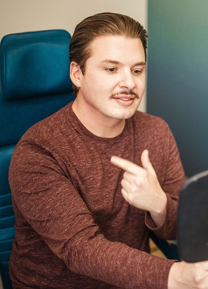Man pointing at mirror while sitting.