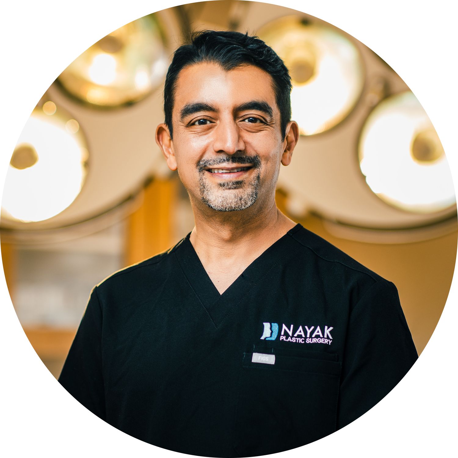 Surgeon in scrubs smiling in operating room.
