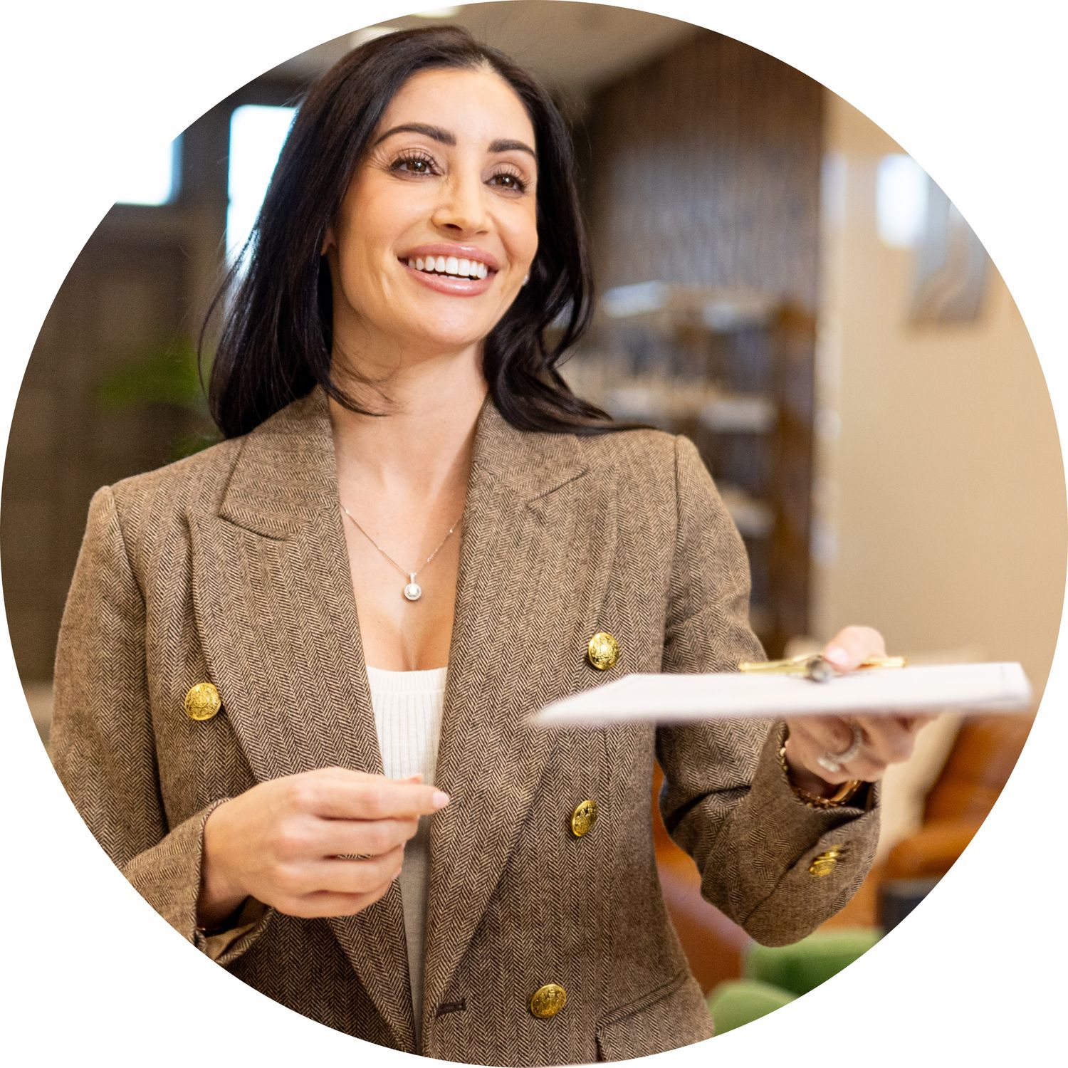Smiling woman in elegant blazer holding a notebook.